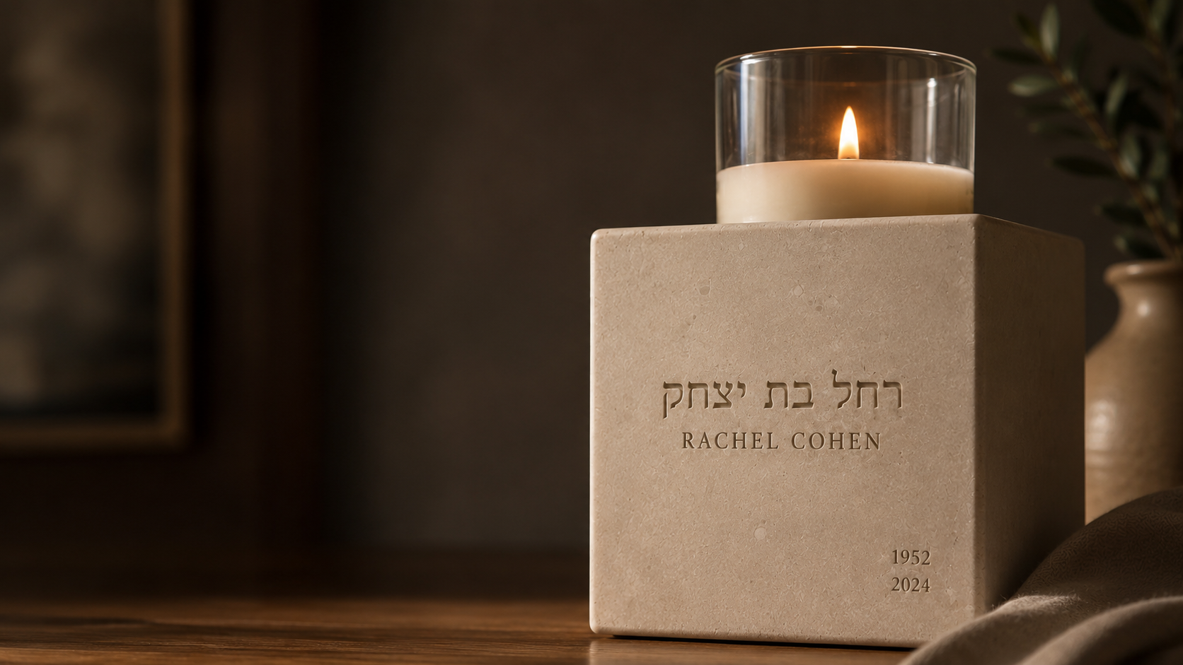 A Neshama Stone with its lit yahrzeit candle casting warm light across carved Hebrew letters.