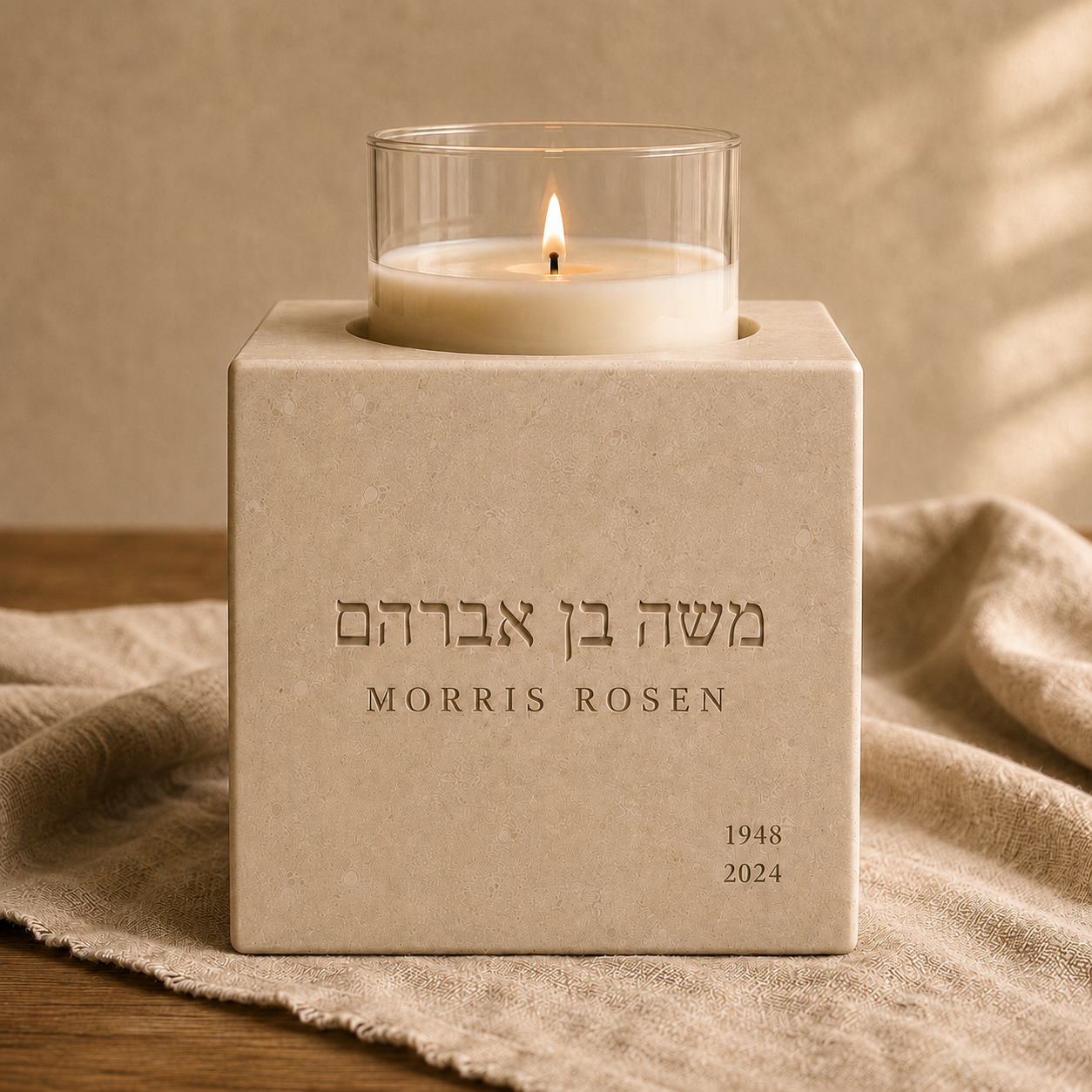The Neshama Stone engraved with a Hebrew and English name, with lit candle, on a warm oak shelf.